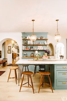 a kitchen with blue cabinets and wooden stools in the center, along with an island