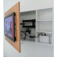 a tv mounted to the side of a white wall next to a shelf with wires