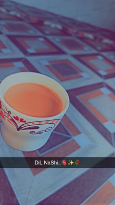 a cup of tea sitting on top of a tiled floor