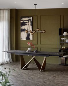 a dining room with green walls and wood flooring that has a modern table in the middle