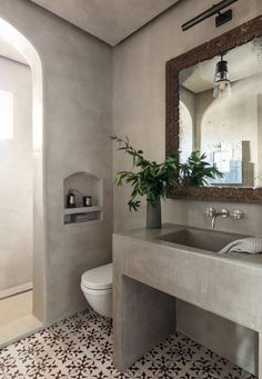 a white toilet sitting next to a bathroom sink under a mirror on top of a wall