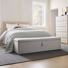 a bed sitting on top of a wooden floor next to a white dresser and window