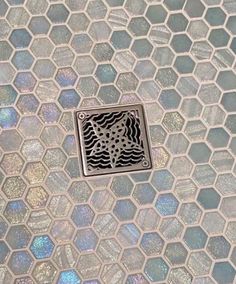 a close up of a shower drain with hexagonal tiles in the floor and ceiling