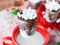 someone is dipping marshmallows into a cup of hot chocolate