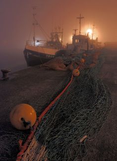 a fishing boat in the fog with its lights on