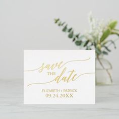 save the date cards with gold foil lettering on white paper next to a vase filled with flowers