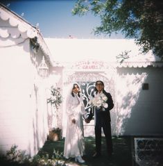 a man and woman standing in front of a white building