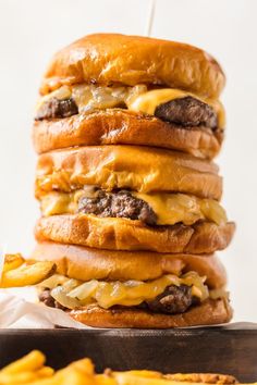 a stack of cheeseburger with fries on the side