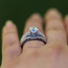 a woman's hand holding an engagement ring with a green stone in the center