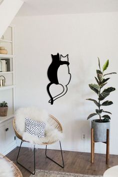 a black cat wall sticker sitting on top of a white wall next to a chair