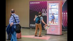 a man standing in front of a pink machine with his hand up to the air