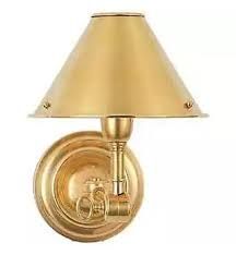 a gold wall light with a shade on it