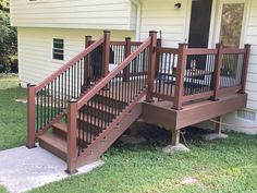 a wooden deck with railing and handrails in front of a house