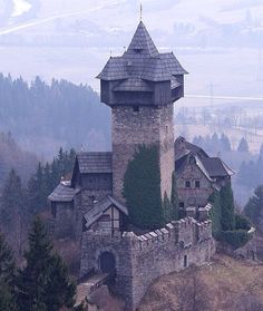 an old castle on top of a hill surrounded by trees and hills in the background