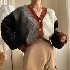 a woman standing in front of a window wearing a sweater with buttons on the back