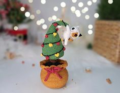 a small crocheted christmas tree sitting in a pot next to a stuffed animal