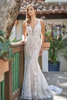 a woman in a wedding dress leaning against a fence