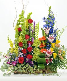 a basket filled with lots of different types of flowers and greenery next to each other