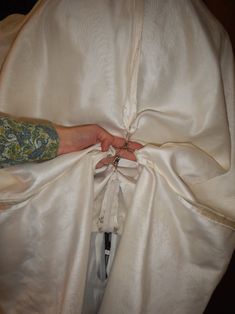 a person's hand pulling up the back of a white bed sheet with their hands