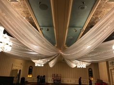 the ceiling is decorated with white drapes and chandeliers