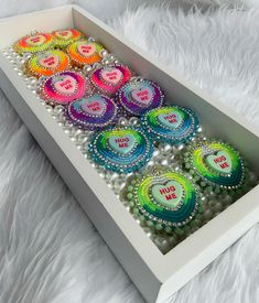 a box filled with lots of different colored buttons and some white pearls on top of it