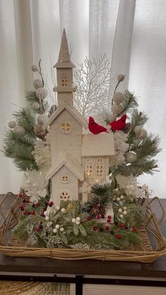 a small white church surrounded by greenery and christmas decorations in front of a window