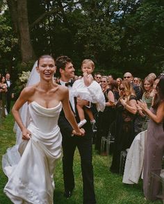 a bride and groom walk down the aisle as guests look on at them from behind