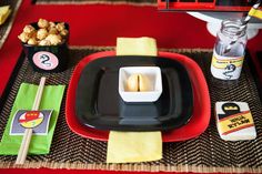 the table is set with black and red plates, yellow napkins, and sushi