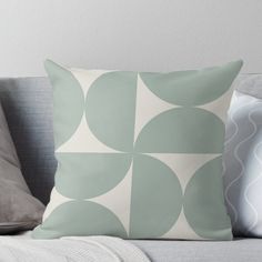 a grey and white throw pillow sitting on top of a gray couch next to pillows