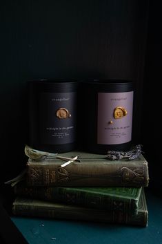 two candles sitting on top of some books next to each other in front of a black wall