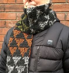 a woman wearing a black and white knitted scarf with an orange design on it