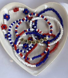 a heart shaped dish with red, white and blue beaded bracelets in the shape of a heart