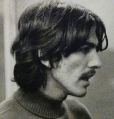 a black and white photo of a man with long hair wearing a turtle neck sweater