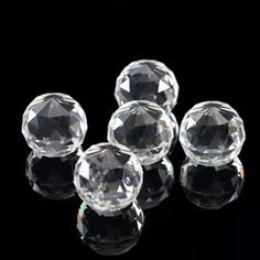 five clear glass knobs sitting on top of a black surface with one facing the camera