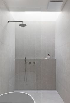 a bathroom with a walk in shower next to a white bathtub and tiled walls