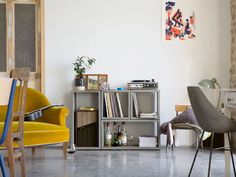 a living room filled with furniture and a book shelf next to a chair in front of a window