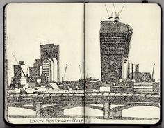 an open notebook with a drawing of a city and bridge in the foreground, along with buildings on either side