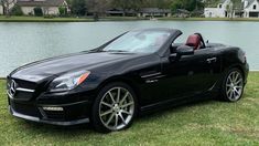 a black mercedes slk parked in front of a lake