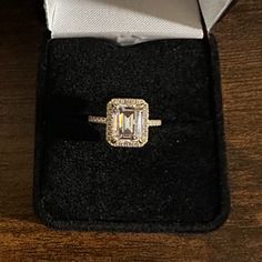 an engagement ring in a box on top of a wooden table with a black velvet case