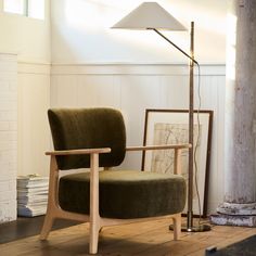 a green chair sitting in front of a lamp on top of a hard wood floor