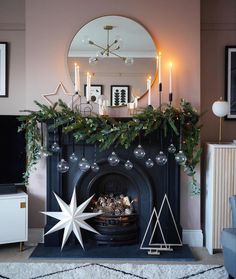 a living room decorated for christmas with candles and decorations on the mantle, including an ornament