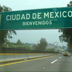 a green sign that reads cuad de mexico on the side of a road with trees and buildings in the background