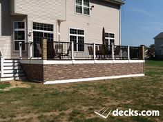 a large white house with a brown and tan brick wall next to it's front porch