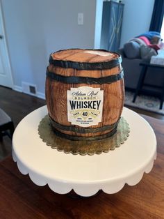 a wooden barrel cake sitting on top of a white cake plate with a sign that says crown royal whiskey