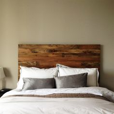 a bed with white sheets and gray pillows