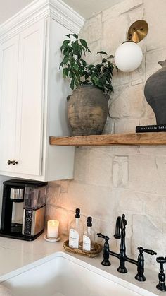 a kitchen with white cabinets and black faucets on the counter top next to a sink