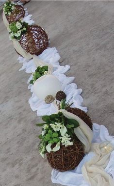 a row of vases with flowers and plants in them sitting on a white cloth