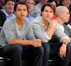 two men sitting next to each other in front of a crowd at a basketball game