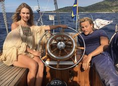 two people are sitting on the deck of a boat and posing for a photo together