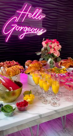 a table topped with lots of food next to a neon sign that says hello gorgeous